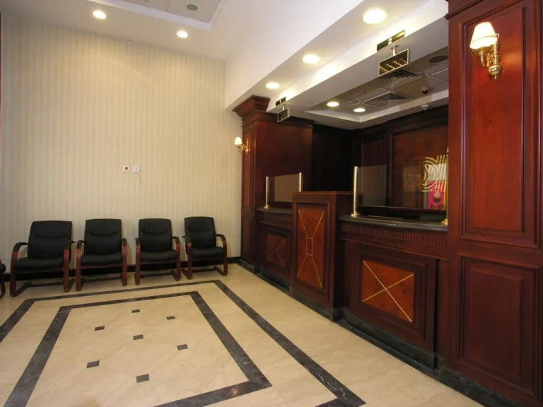 Customer service counter in bank interior design featuring wooden finishes and an integrated queue management system.